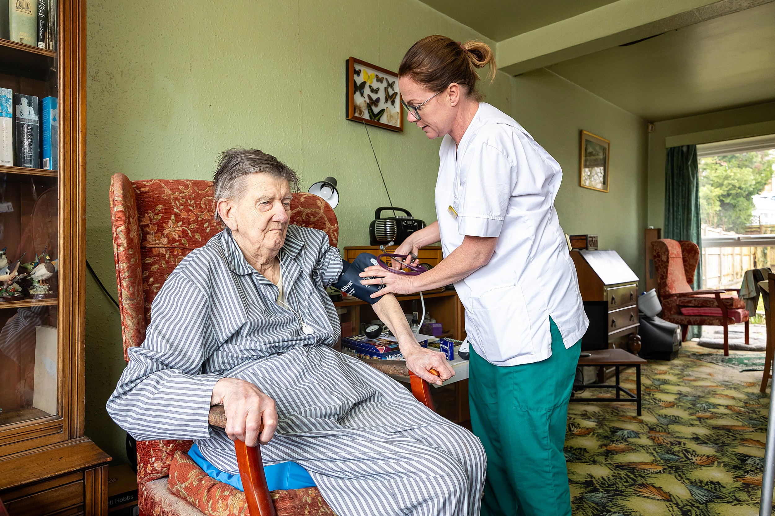 A healthcare worker is checking resident blood pressure