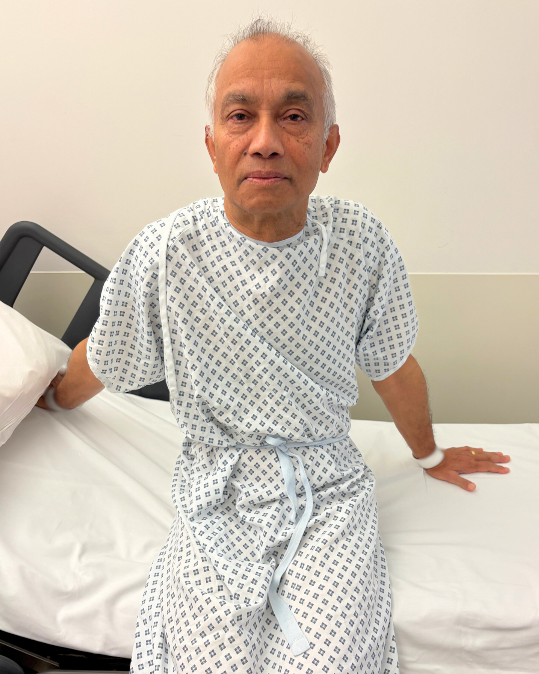 Harry Matadeen seated on a bed in a hospital gown