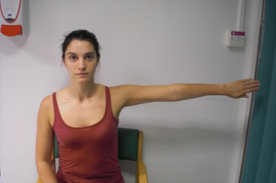 Person seated with one arm out to side, palm facing backwards