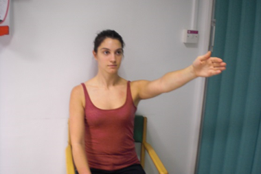 Person seated with one arm held out in front and raised above shoulder height.