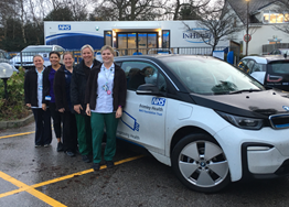 Staff by one of the Trust's electric cars