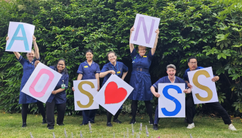 Group of uniformed nurses holding signs reading A O S N S S plus a heart